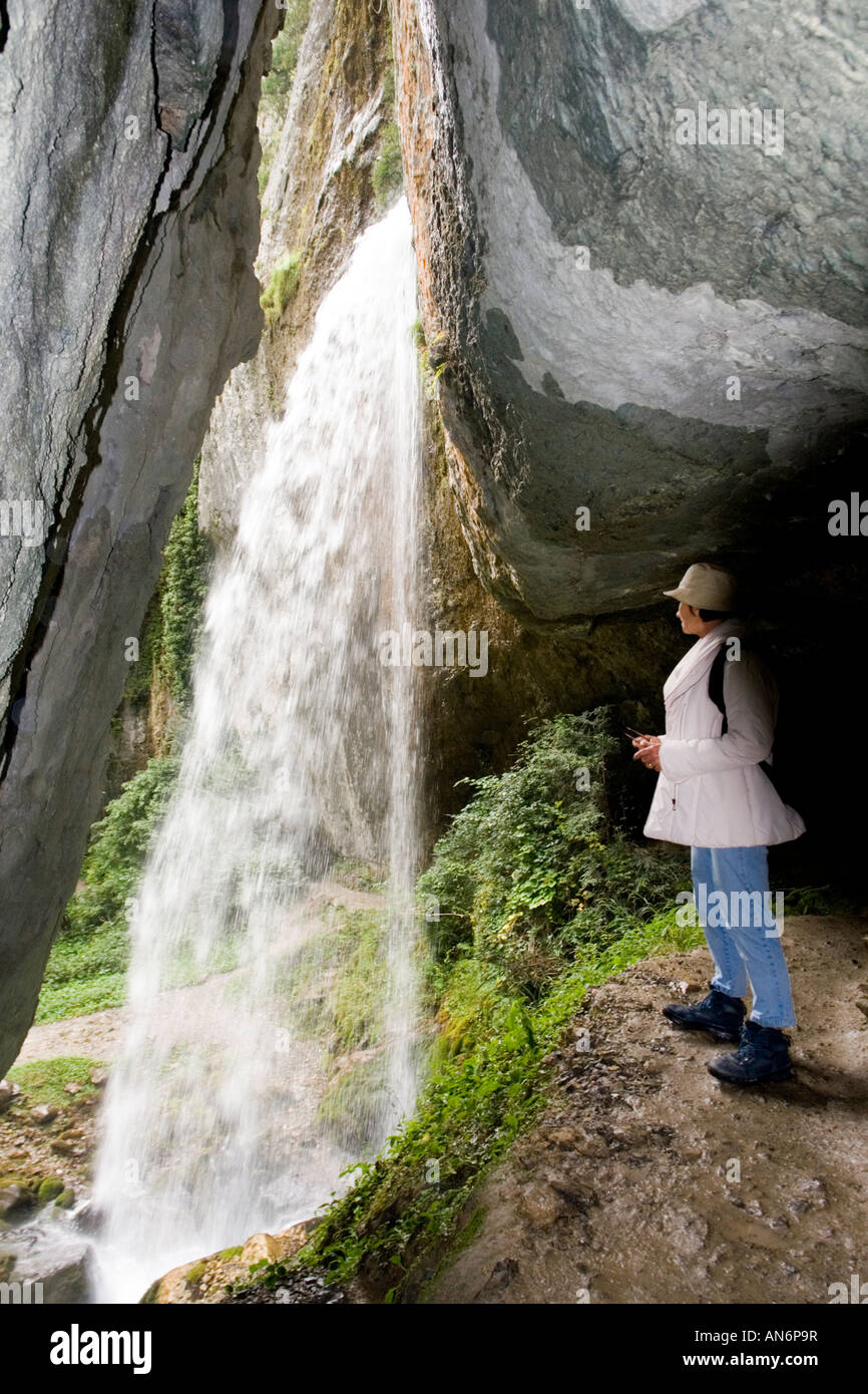 Une dame de derrière la cascade de Kakouetta (France). Une touriste admirant la chute d'eau de Kakouetta (France). Banque D'Images
