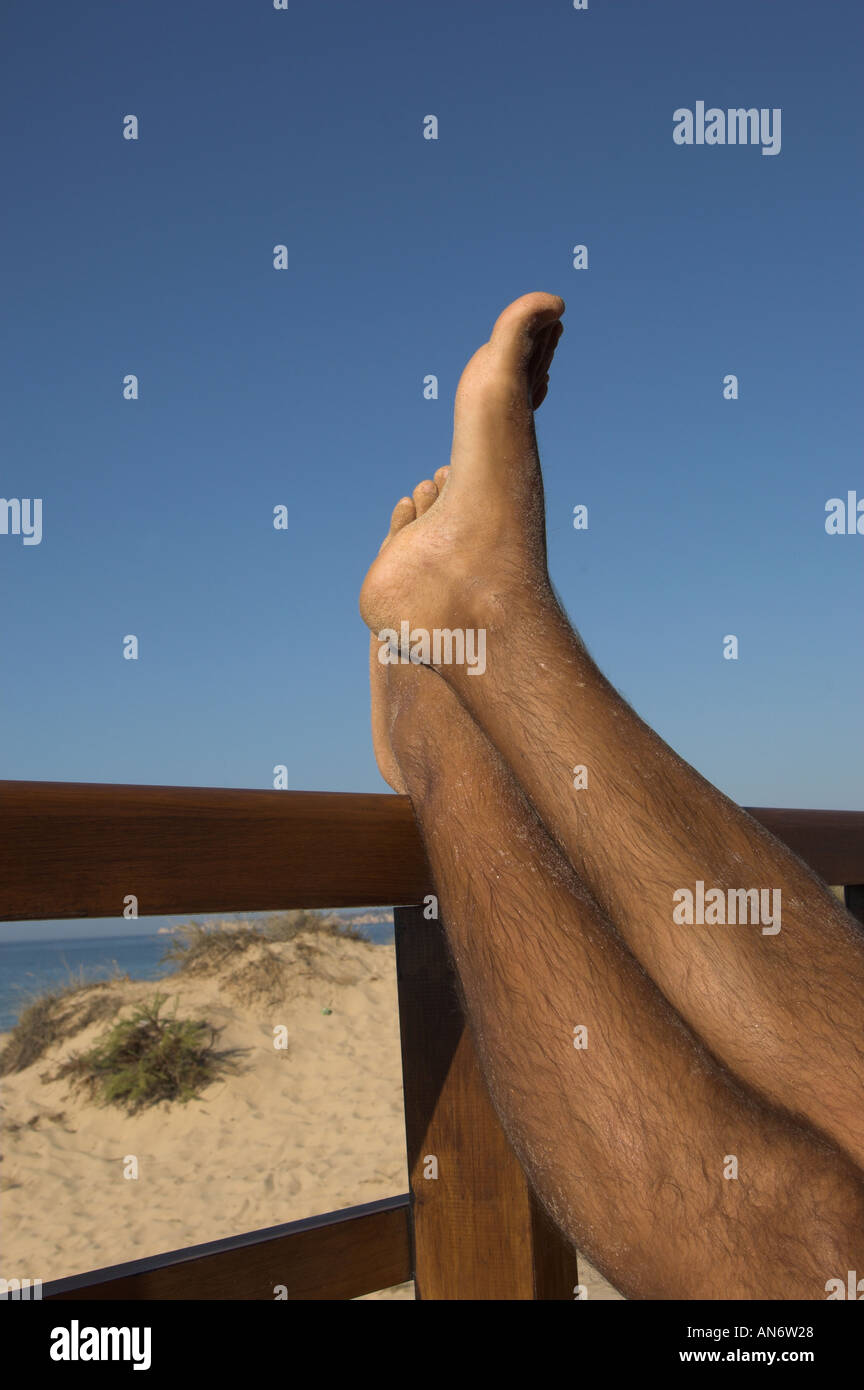 Pieds de l'homme soulevées dans l'air, reposant sur une structure de bois, jambes croisées Banque D'Images