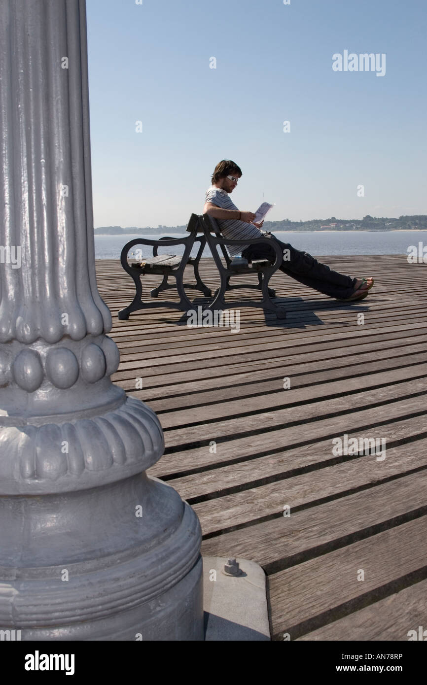 Livre tout en lecture mâle assis sur banc Banque D'Images