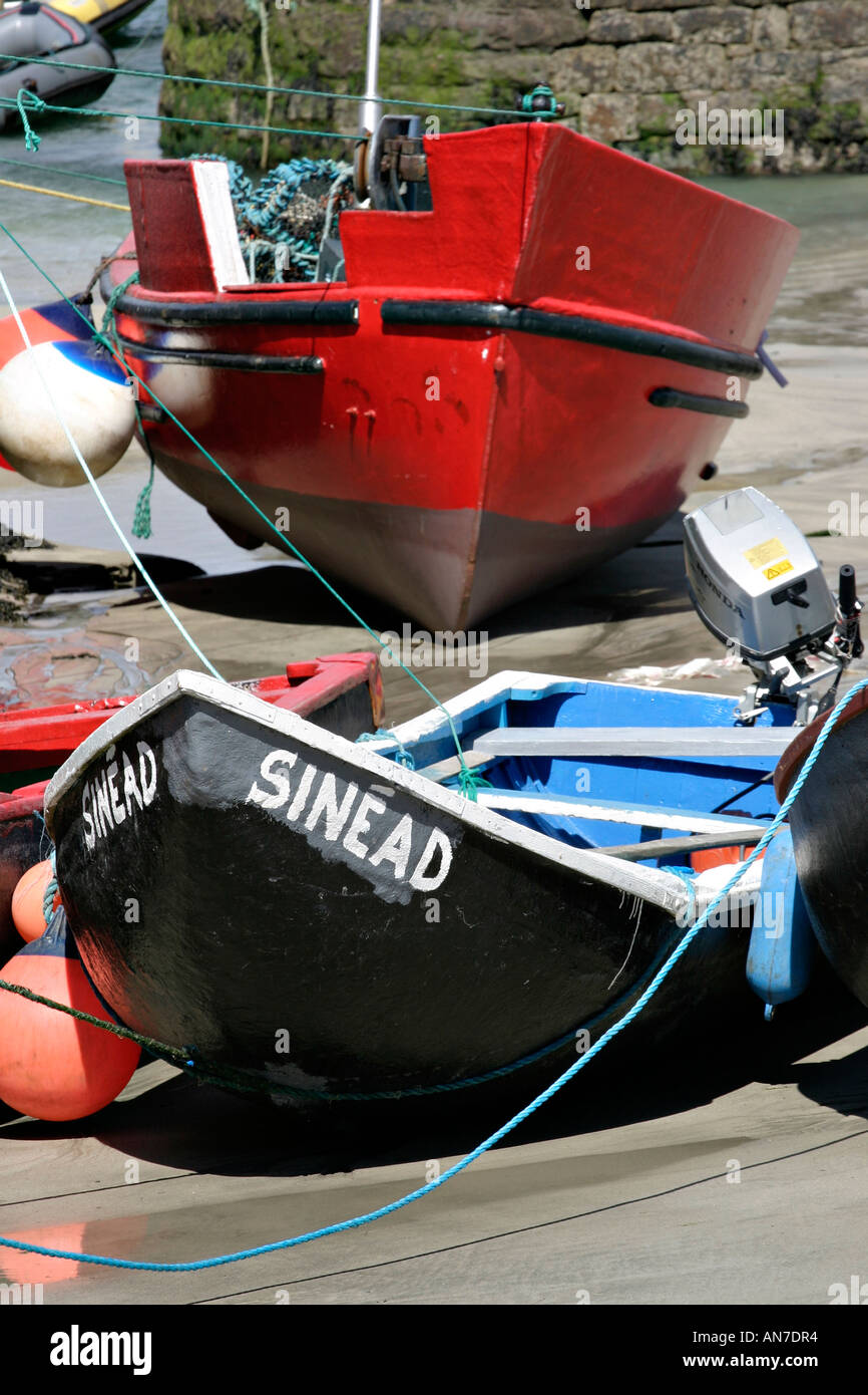 Un ancien style currach pêche nommé Sinead et un plus grand bateau rouge à la fois échoué sur le fond sablonneux Banque D'Images