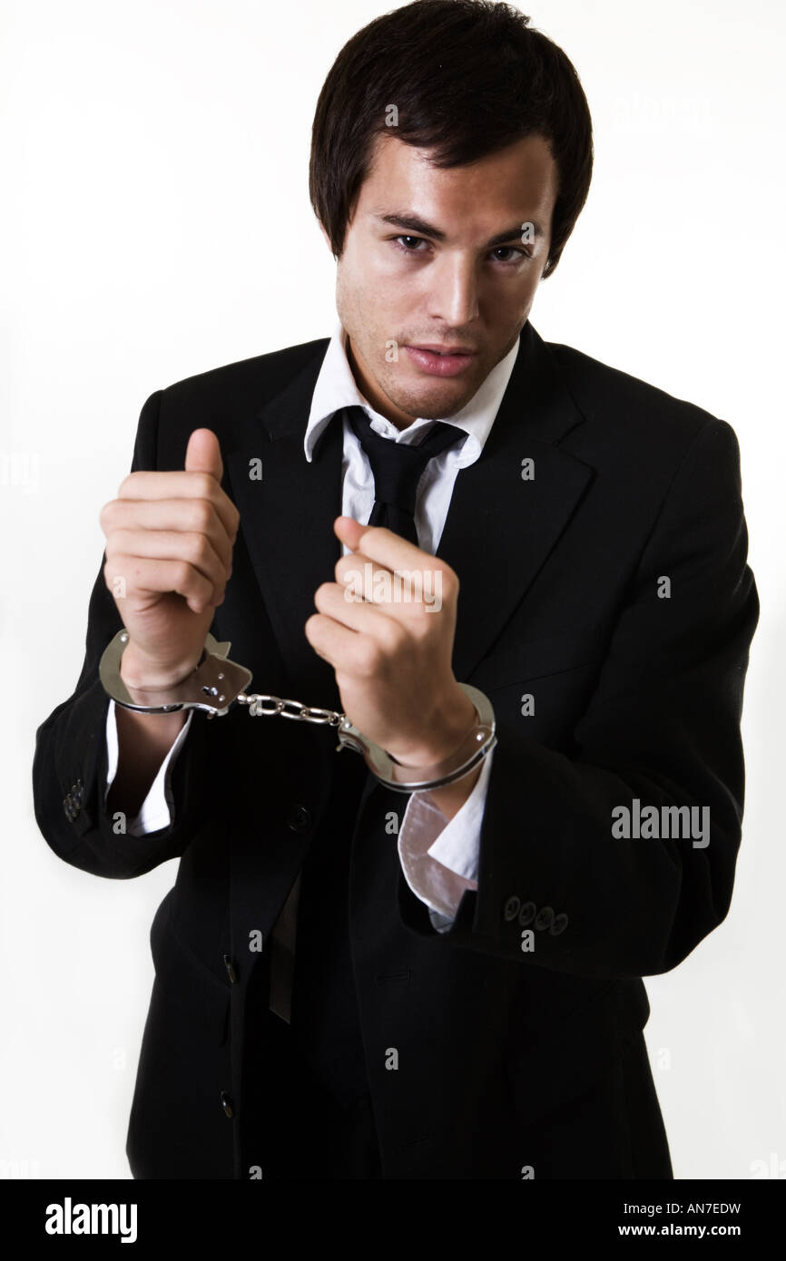 Jeune homme d'affaires Professionnel en tailleur avec les mains dans des menottes montrant un collier blanc crime Banque D'Images