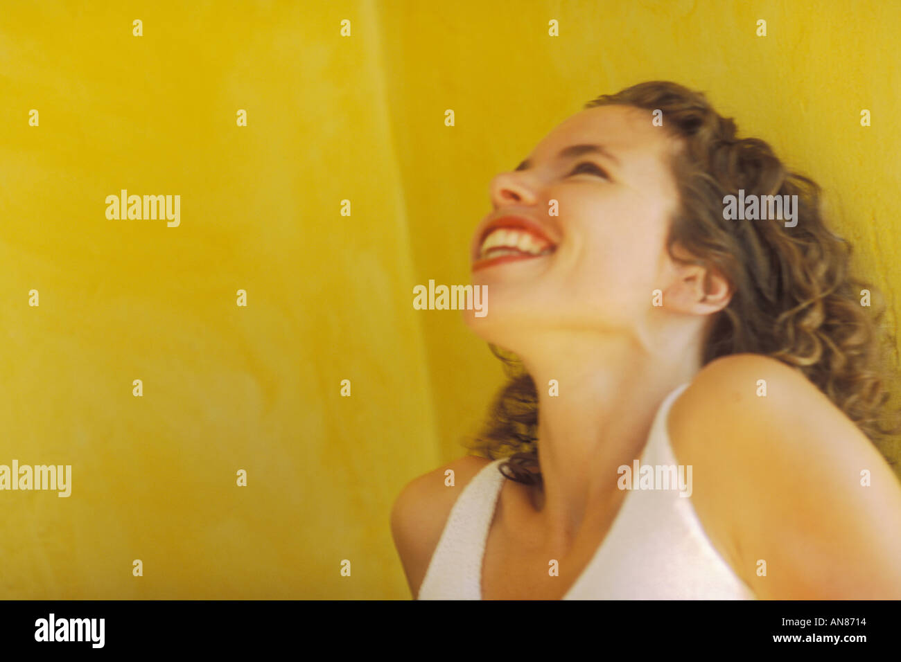 Portrait 27 ans mixed Hispanic female rire contre mur jaune Banque D'Images
