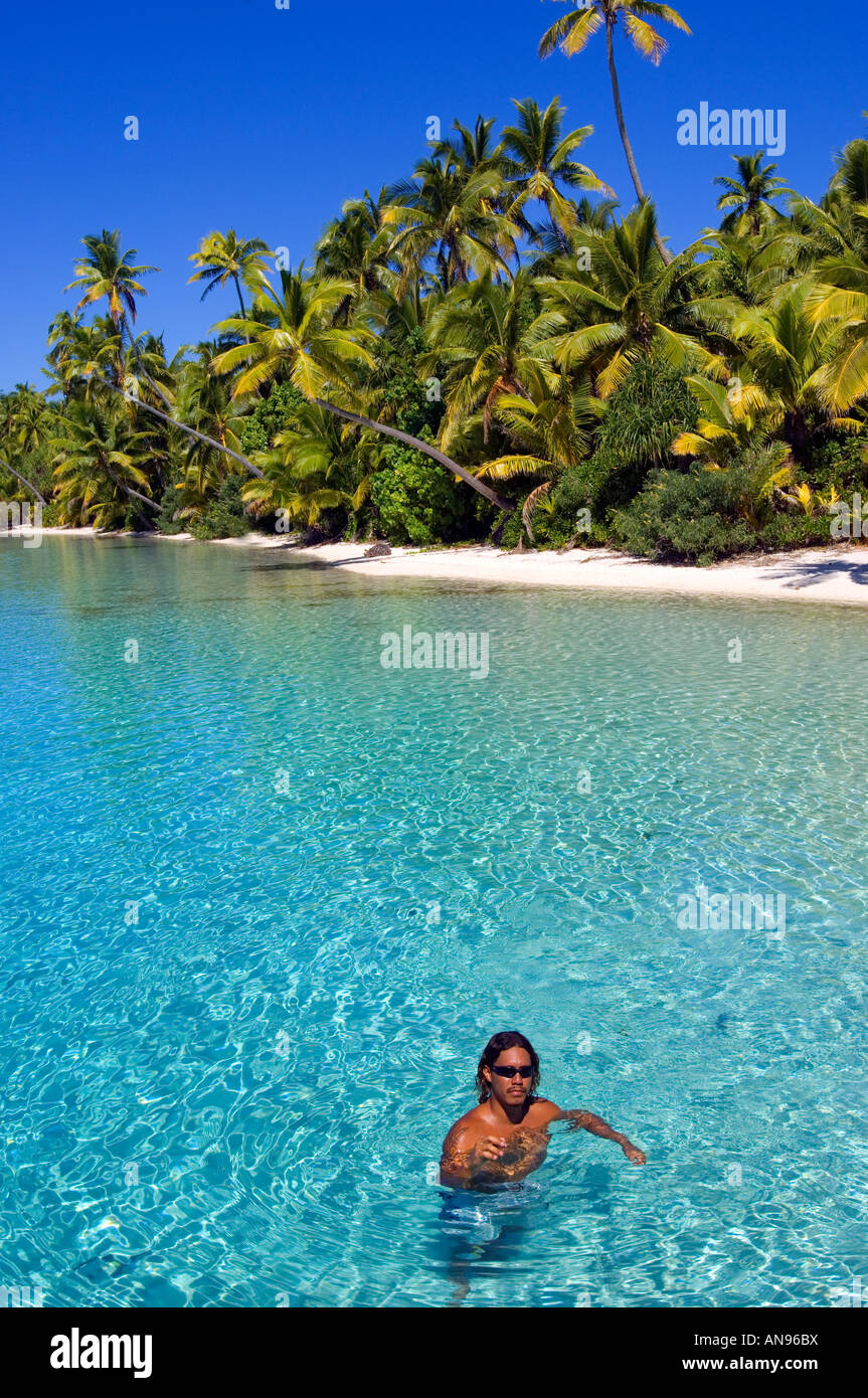 Homme polynésien dans l'eau au large d'une plage de cartes postales bordée de palmiers dans l'atoll isolé d'Aitutaki Cook Islands Banque D'Images