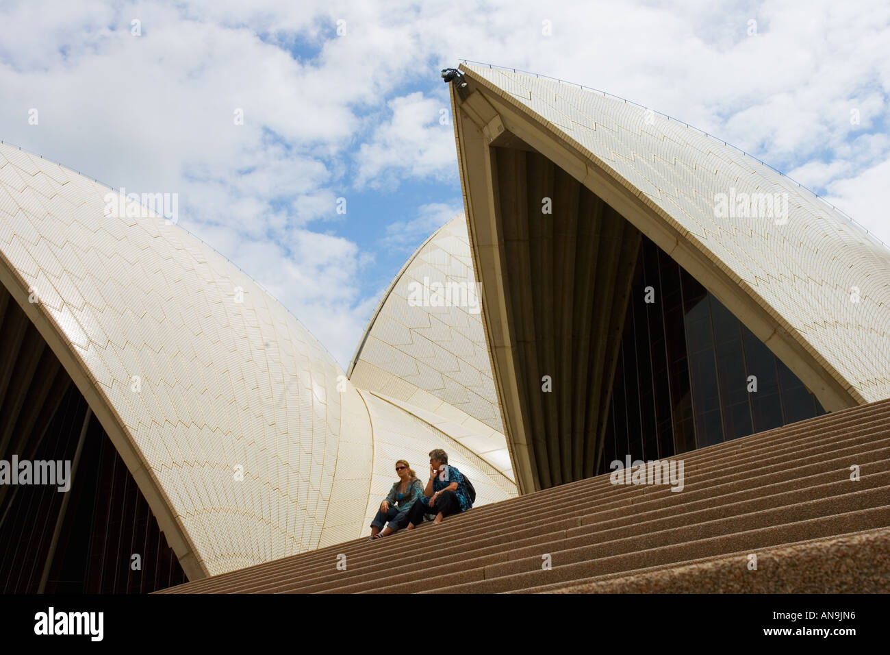 Les touristes s'asseoir sur les marches en face de l'Opéra de Sydney, Australie Banque D'Images