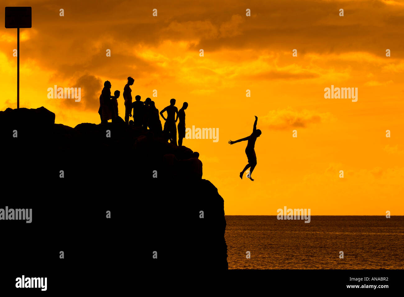 Silhouette d'enfants en train de sauter du Rocher à Waimea Bay, Oahu Hawaii Banque D'Images
