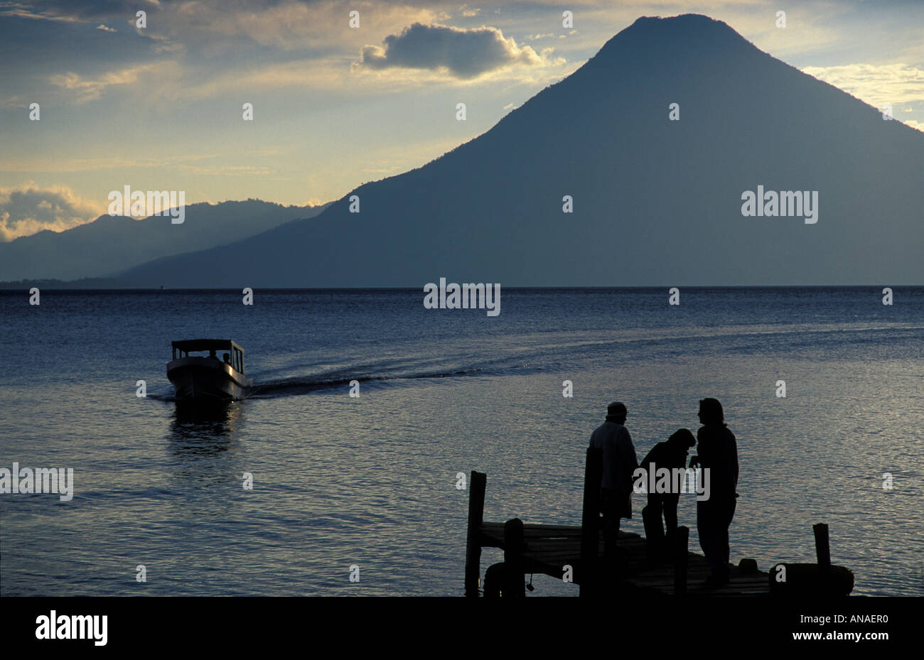 Les touristes à la fin d'une jetée qui se profile au coucher du soleil Panajachel Lac Atitlan Guatemala Bateau et volcan San Pedro au-delà Banque D'Images