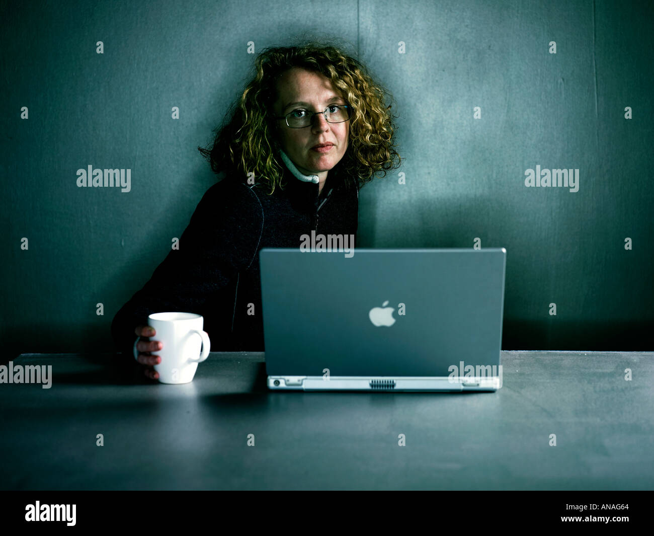 Femme assise à son ordinateur portable avec une tasse de boisson Banque D'Images