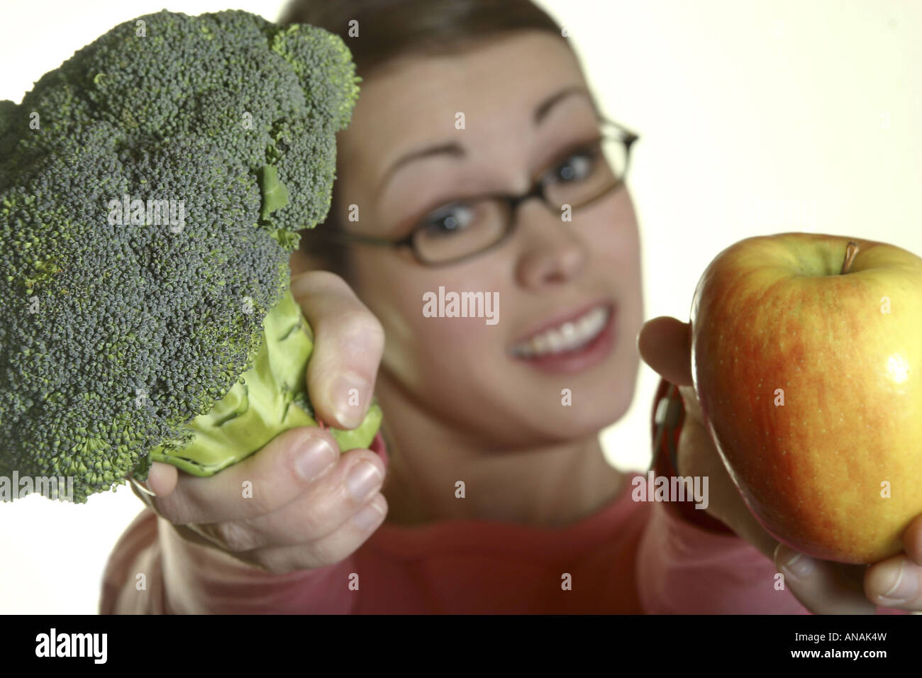 Jeune femme présentant une pomme et brocoli Banque D'Images
