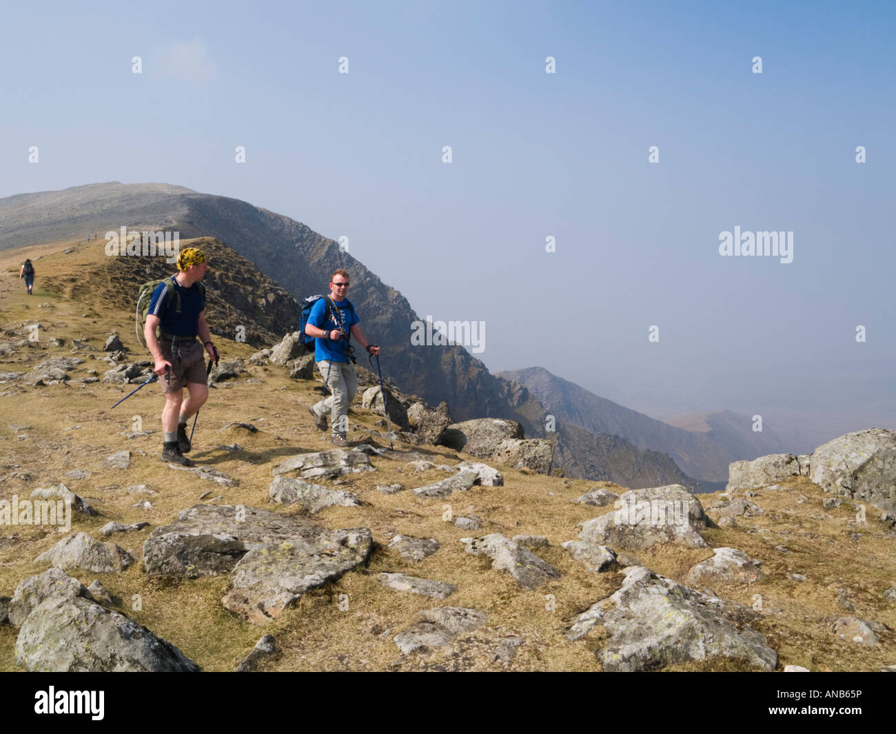 Deux hommes marcher rocky path sur la descendance d'Carnedd Dafydd avec vue de Mynydd Du ridge dans les montagnes Carneddau au-delà. Le Parc National de Snowdonia au Pays de Galles UK Banque D'Images