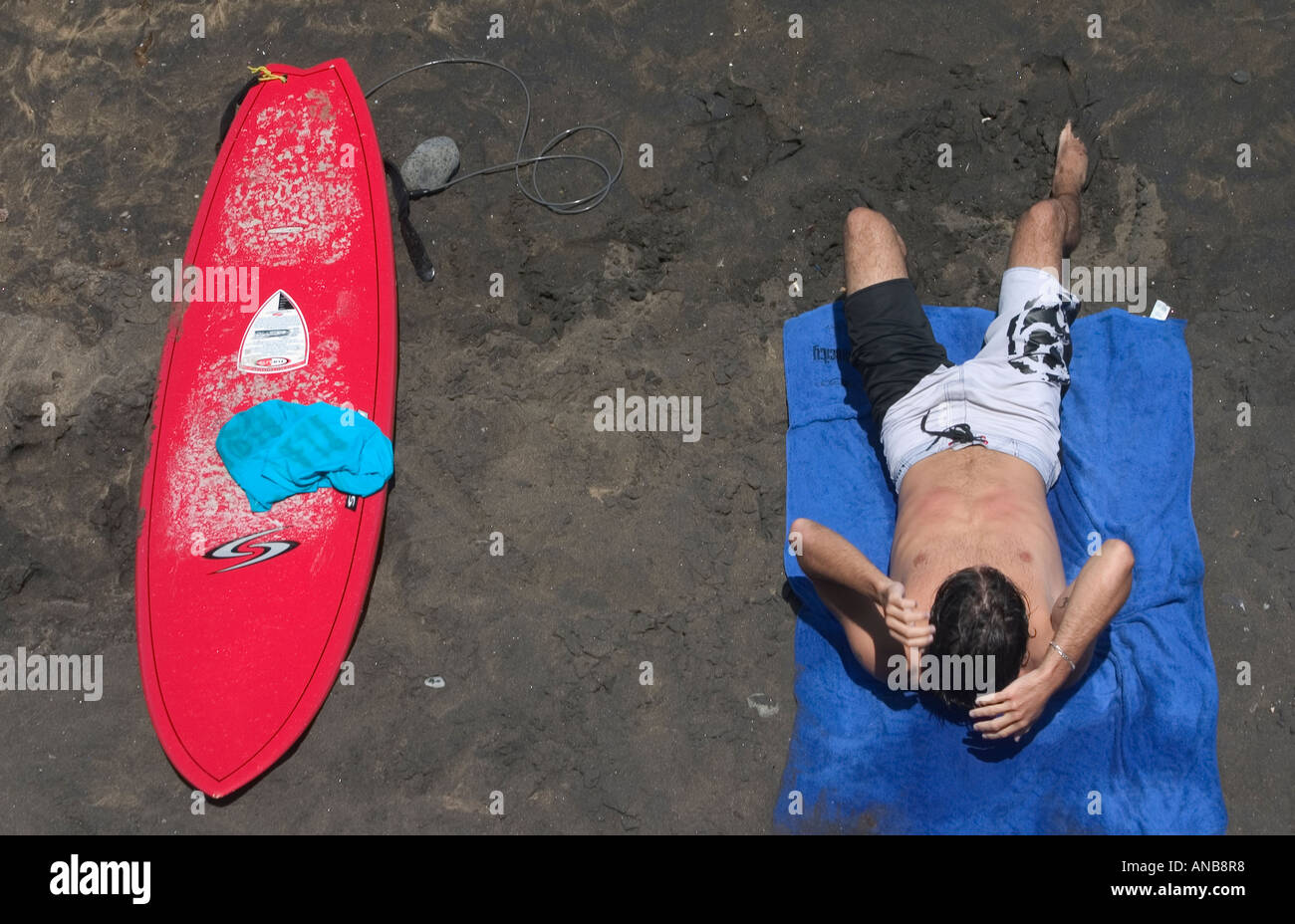 Surfer à la plage à côté de planche de surf Banque D'Images