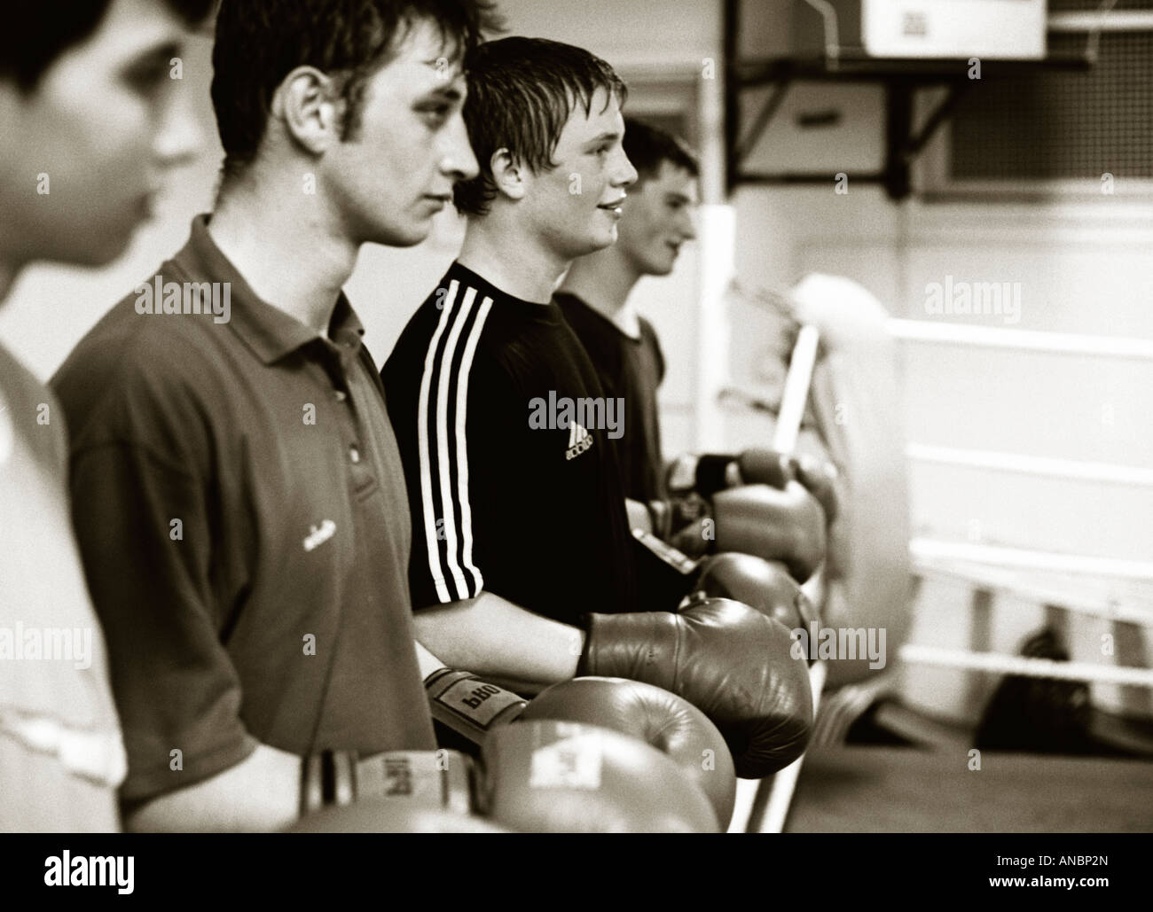 Un paysage en noir et blanc de quatre boxeurs adolescentes l'écoute et l'apprentissage au cours d'une session de formation à leur sport. Banque D'Images