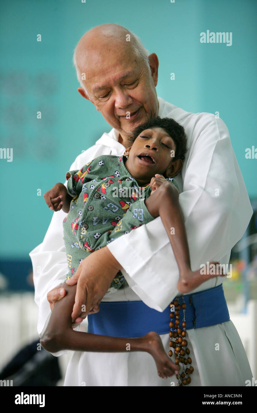 Le Père Richard Ho Lung, fondateur et chef de la 'Missionaries congrigation catholique romaine des pauvres' avec l'enfant handicapé Banque D'Images