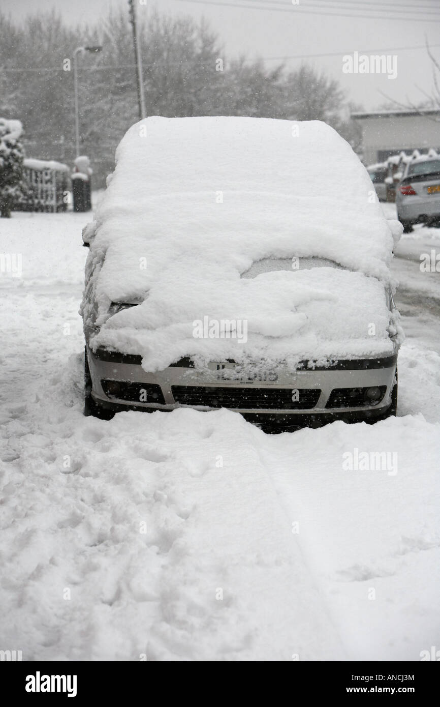 Monospace voiture garée abandonné le long de la route dans une rue couverte de neige lourdes Banque D'Images