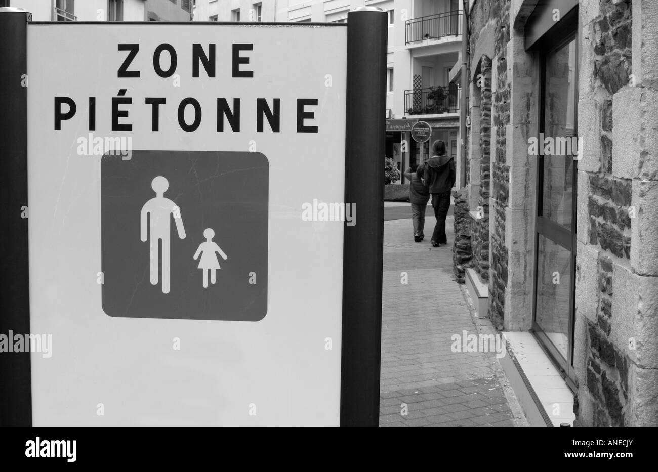 Un adolescent propulsant un jeune garçon le long d'une seule rue piétonne dans la France provinciale Banque D'Images