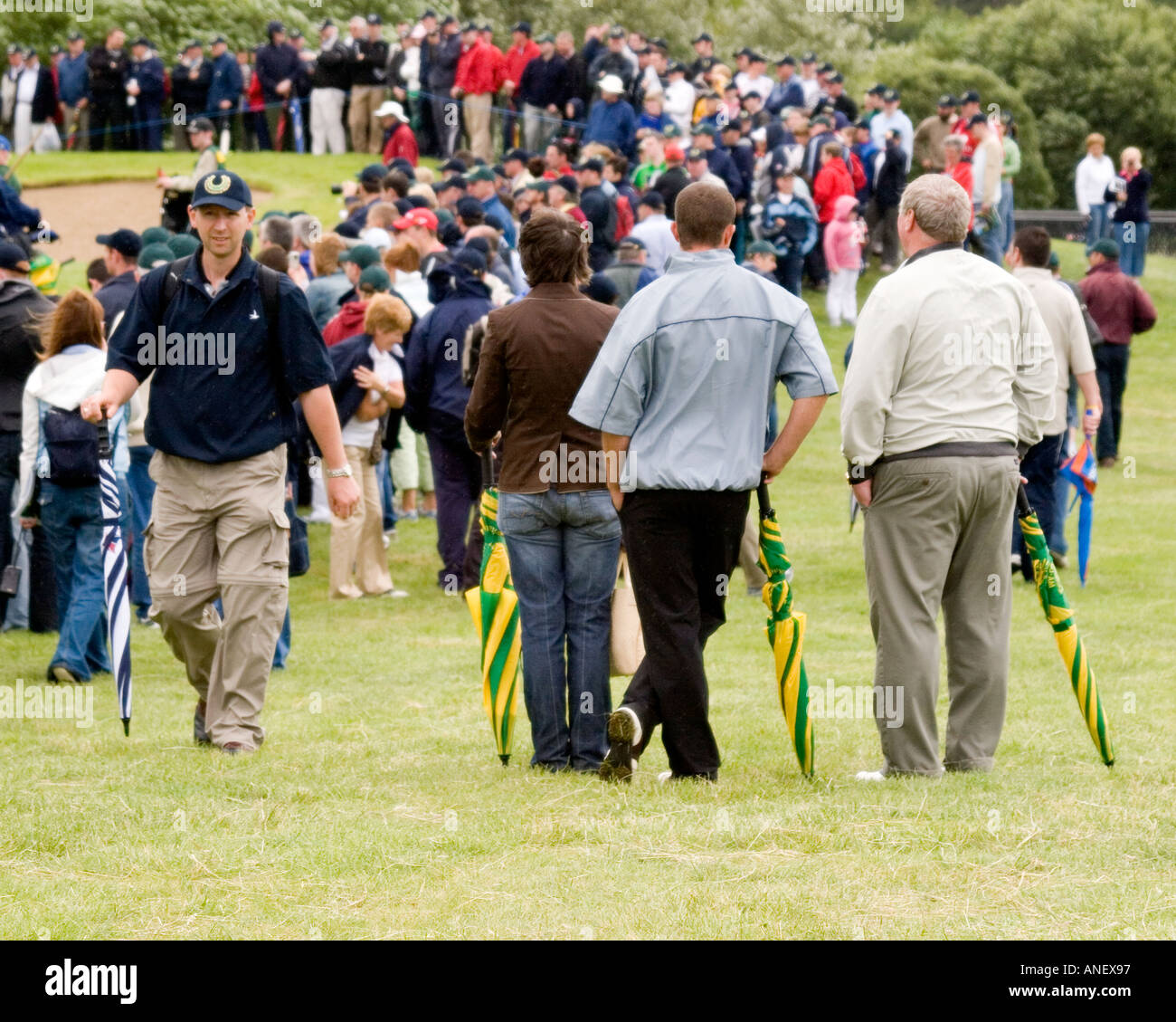 Spectateurs Le golf s'appuyant sur trois parapluies vert et jaune. Limerick, Irlande. Banque D'Images