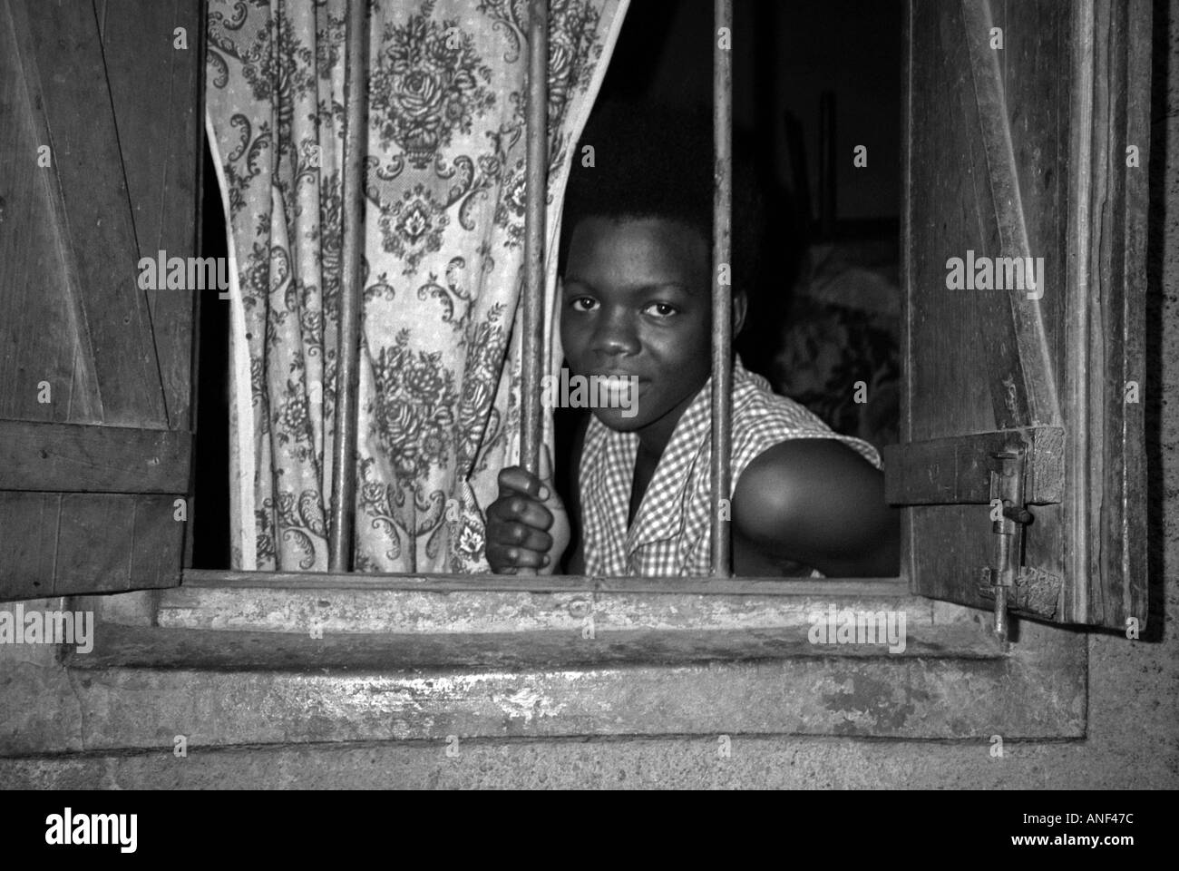 Souriante jeune femme du bidonville d'Acholy quart à la fenêtre de sa cabane en bois Kampala Ouganda Afrique de l'Est Banque D'Images