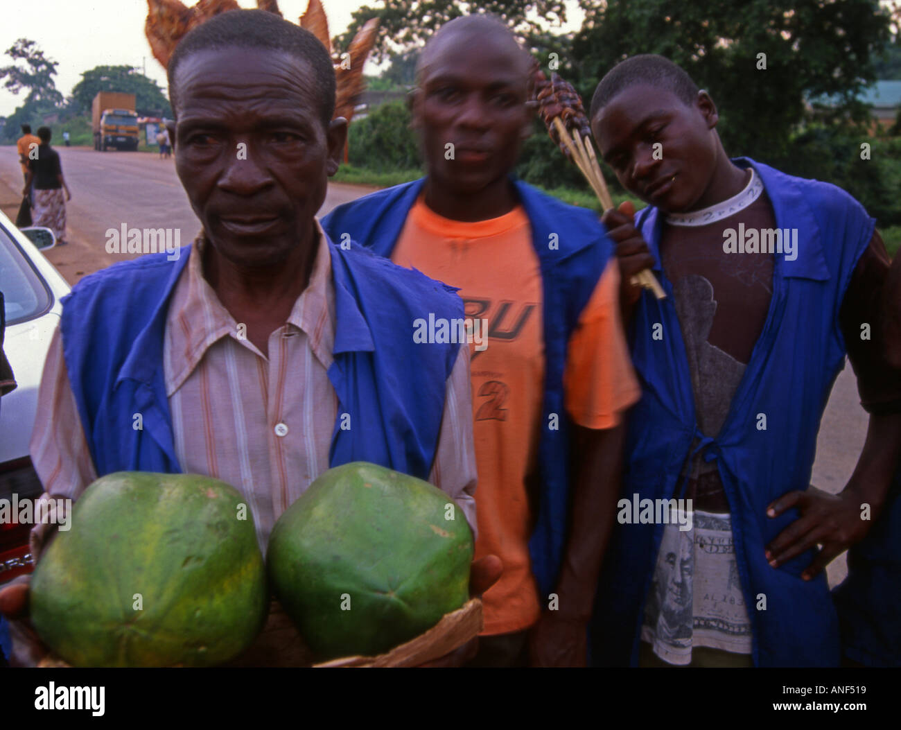 Groupe d'hommes vendeur de rue offrant un poulet rôti aux fruits et de la viande de boeuf à la route près de Tororo Ouganda Kenya Afrique de l'Est Banque D'Images