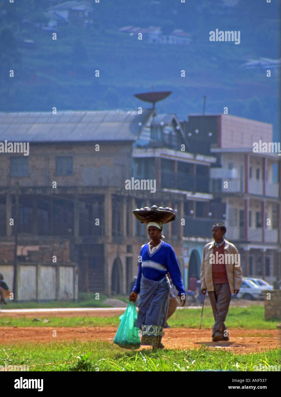 Les femme en costume traditionnel à pied porter panier de fruits sur la tête sur l'Afrique de l'Est Ouganda Kabale frontière Banque D'Images