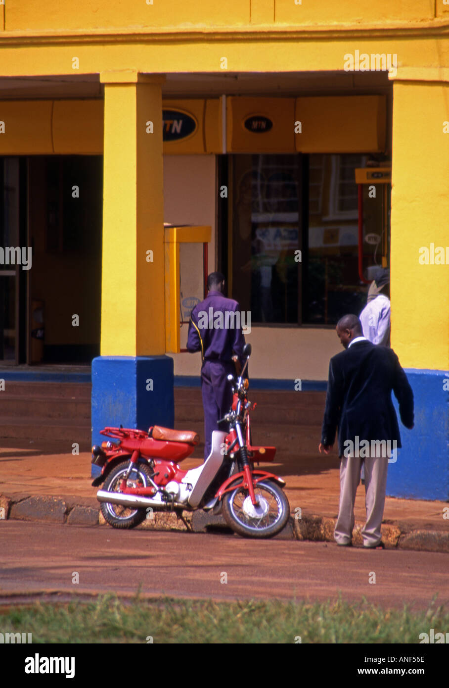 Scène de rue avec le détail de l'architecture coloniale typique colonnade & & les gens qui vaquent à l'homme de la ville de Jinja en Ouganda Afrique de l'Est Banque D'Images