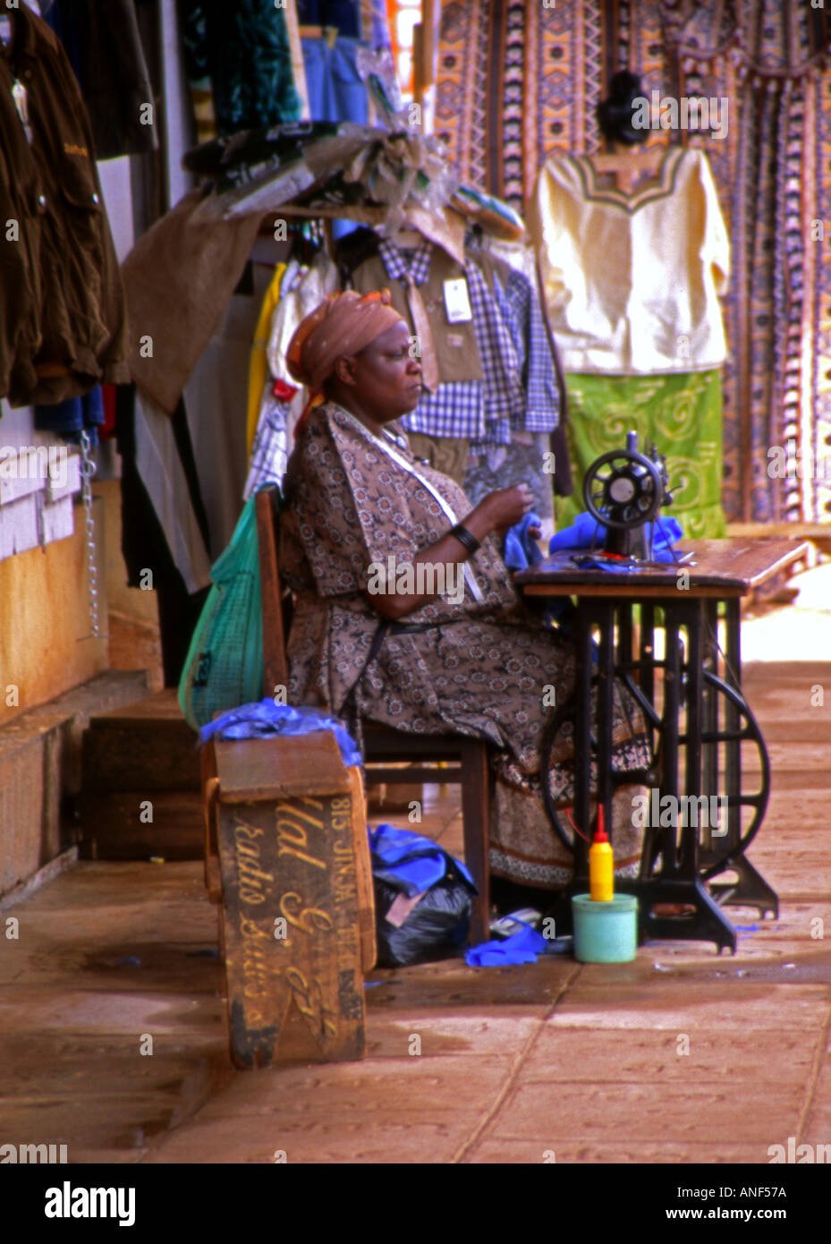 Tailleur rue femme en vêtements traditionnels colorés à l'extérieur de travail machine à coudre ancienne de la ville de Jinja en Ouganda Afrique de l'Est Banque D'Images