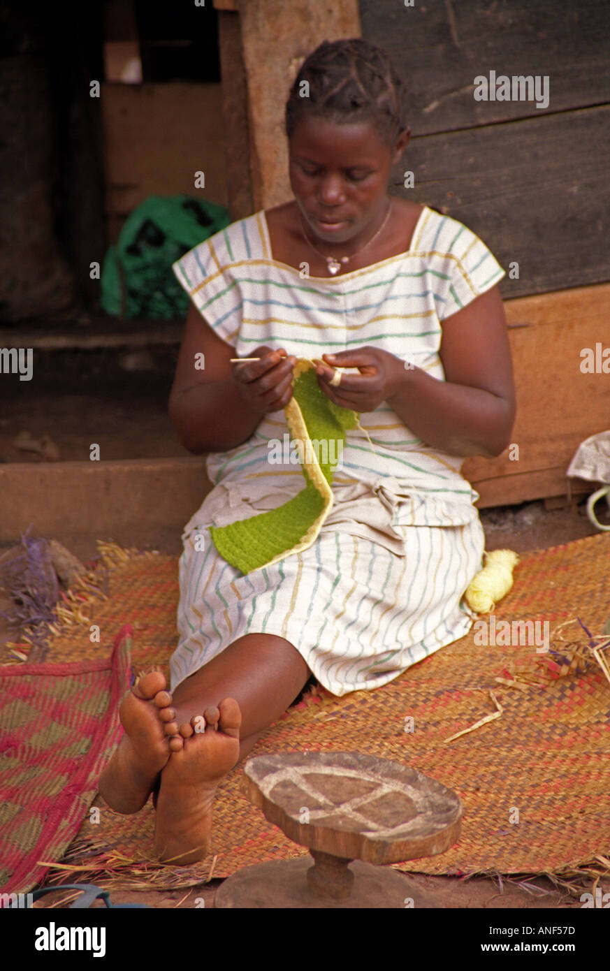 Jeune femme d'Acholy bidonville s'asseoir sur la paille a volé le tricot en plein air par patiemment cabane en bois Kampala Ouganda Afrique de l'Est Banque D'Images