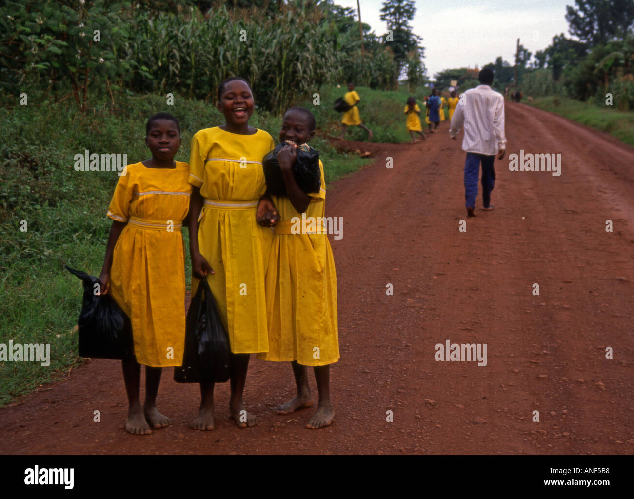 Groupe Portrait fille de l'école à pied aller à l'extérieur pose pied nu couleur uniforme jaune sac hold rire Mwanza Tanzanie Afrique de l'Est Banque D'Images