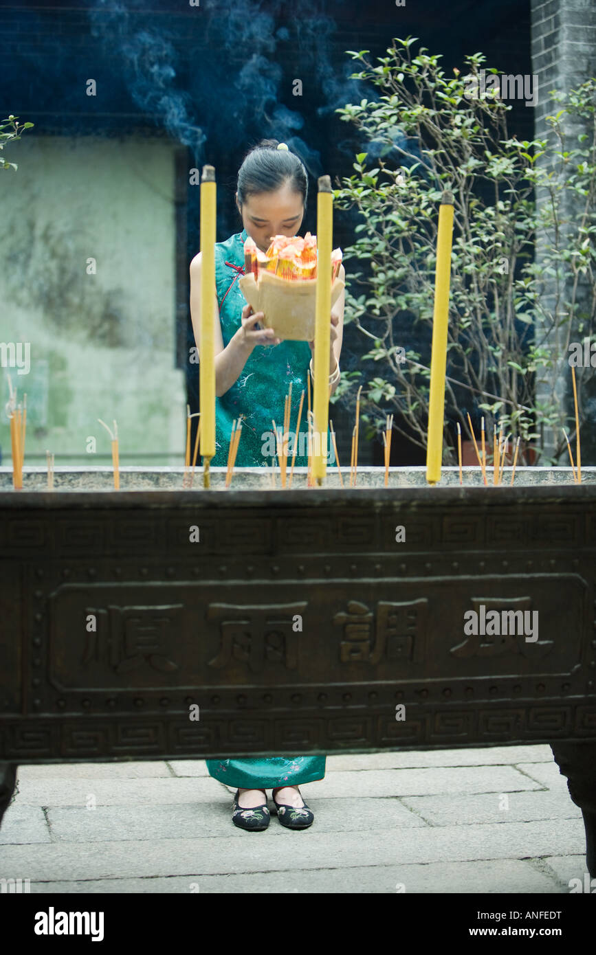 Young woman holding up, cour du temple offrande religieuse, les yeux fermés et la tête inclinée Banque D'Images