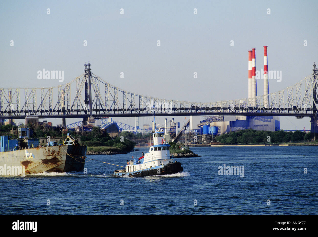 Remorqueur de East River tirant une scierie, pont de Manhattan, usine d'électricité de con Edison, centrale électrique de Ravenswood, en arrière-plan.Queens, New York, États-Unis Banque D'Images