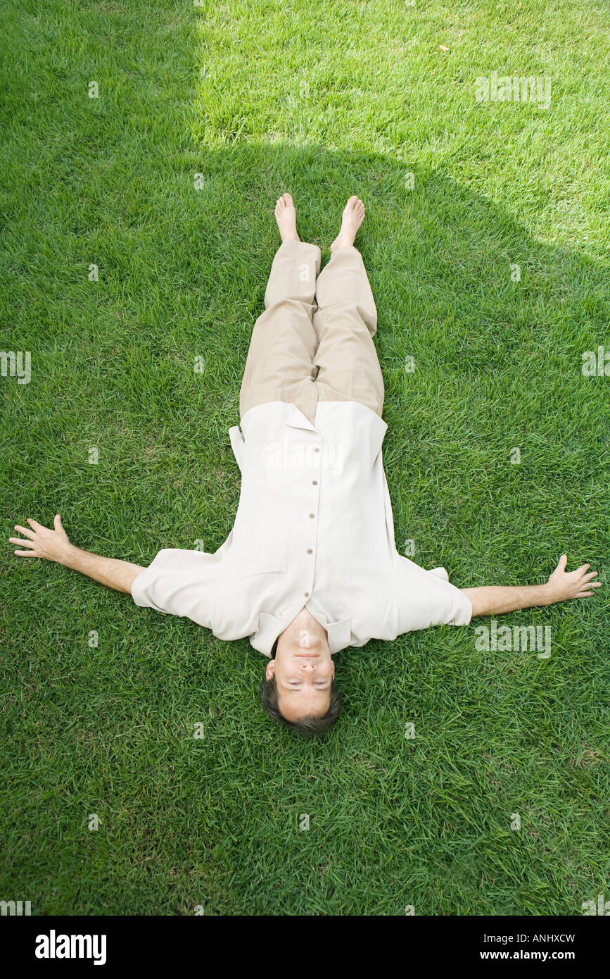 L'homme allongé sur le dos dans l'herbe, smiling at camera, portrait Banque D'Images