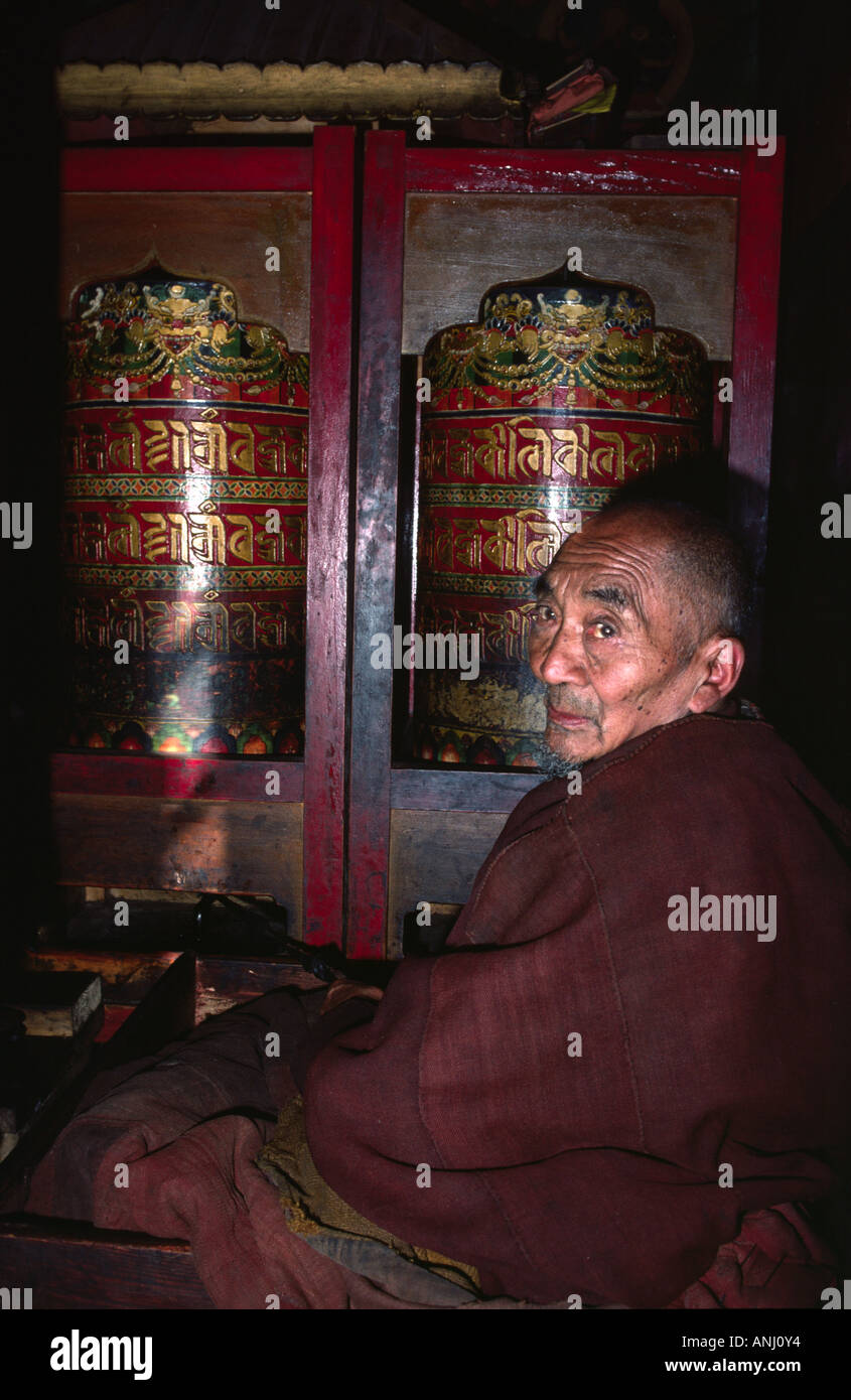 Portrait d'un moine tibétain âgé qui tourne des roues de prière bouddhistes traditionnelles dans un monastère de la région reculée du Ladakh dans le nord de l'Inde Banque D'Images