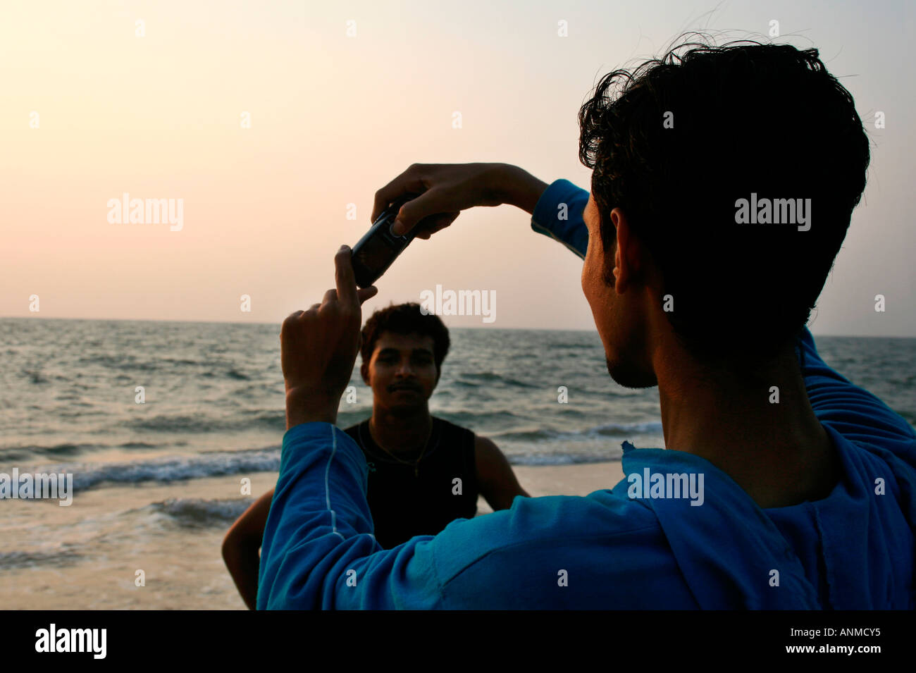 Un garçon qui pose pour une photographie prise par son ami sur un téléphone mobile dans le contexte de la mer à l'Alapuzha Beach Kerala Banque D'Images