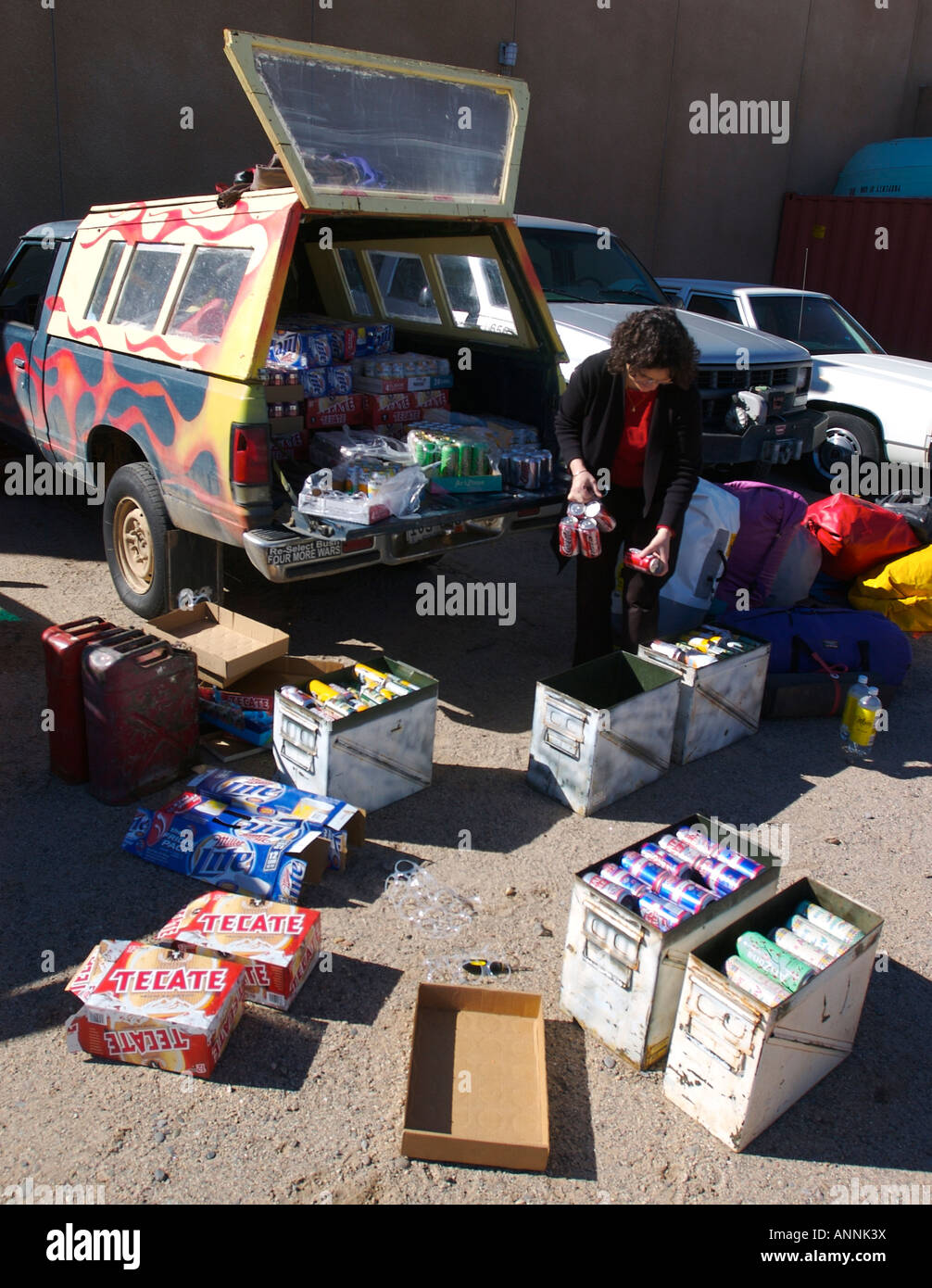 Woman packing plusieurs dizaines de caisses de bière et de jus de fruits en surplus d'armée rocket boîtes pour un voyage de rafting en eau vive Banque D'Images