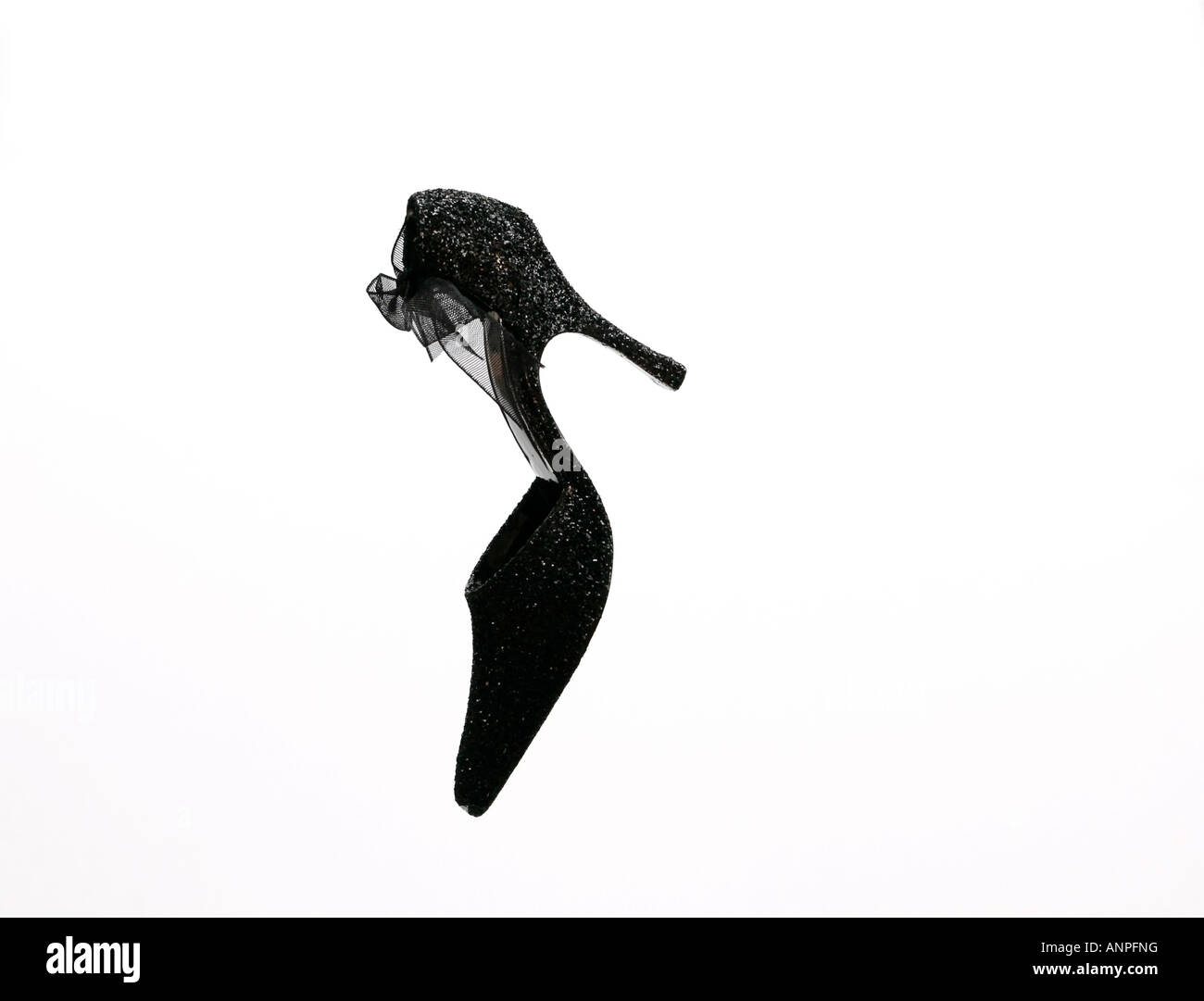 Portrait d'une chaussure en forme de stiletto à paillettes noires avec noeud noir sur fond blanc Uni Banque D'Images