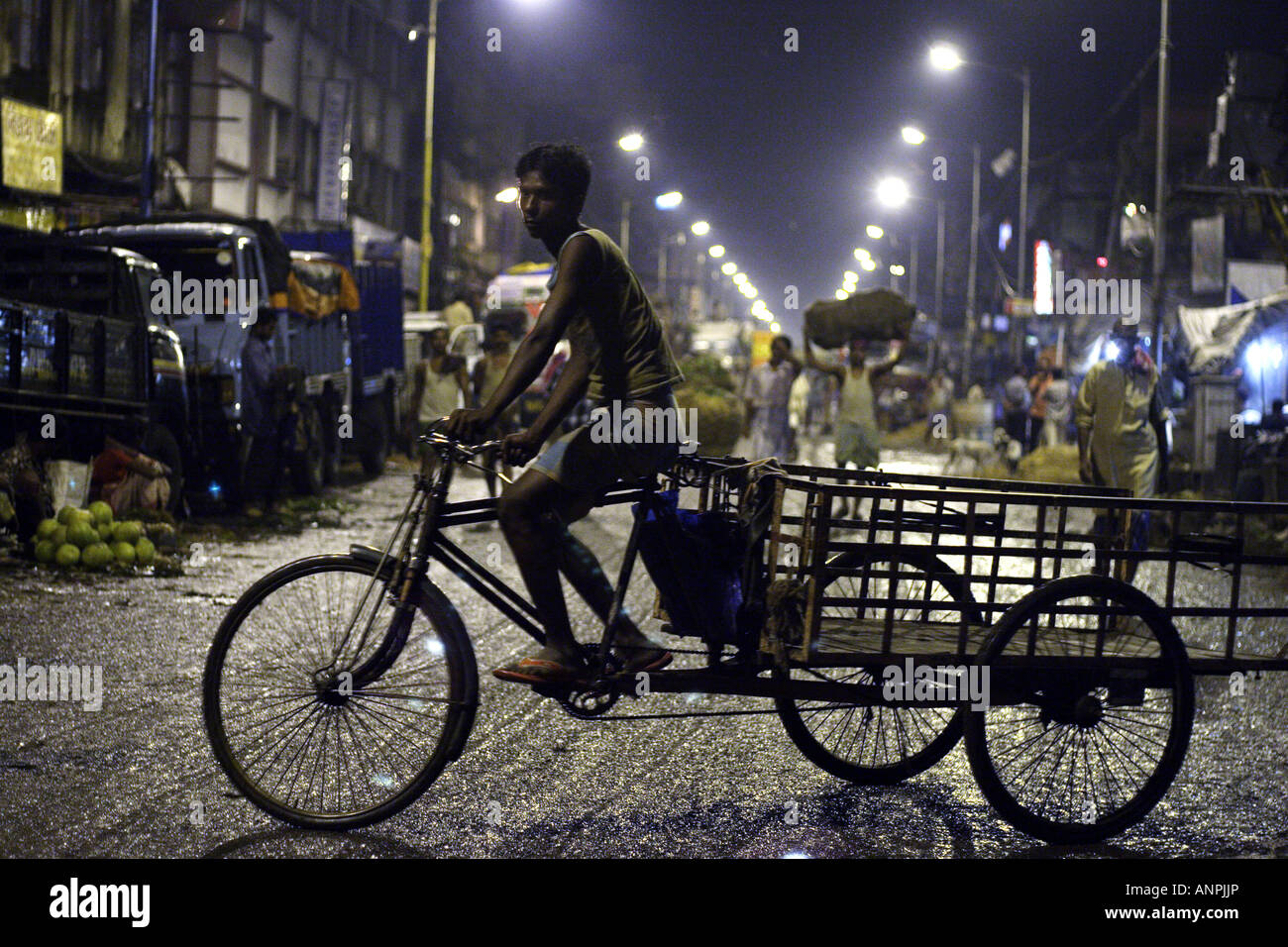 Un homme monte un tricycle sur une rue à proximité du marché de gros pour les fruits et légumes à Kolkata, Inde. Banque D'Images