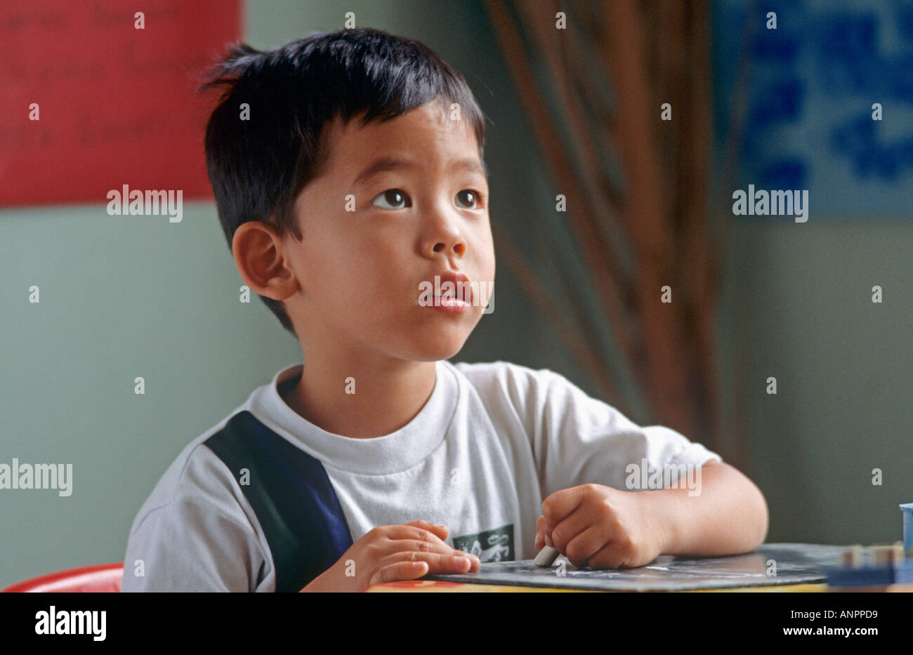 CLASSE INFANTILE ÉCOUTANT quatre ans bébé coréen oriental écolier en uniforme avec craie classe maternelle regarde le professeur d'art de la classe Banque D'Images