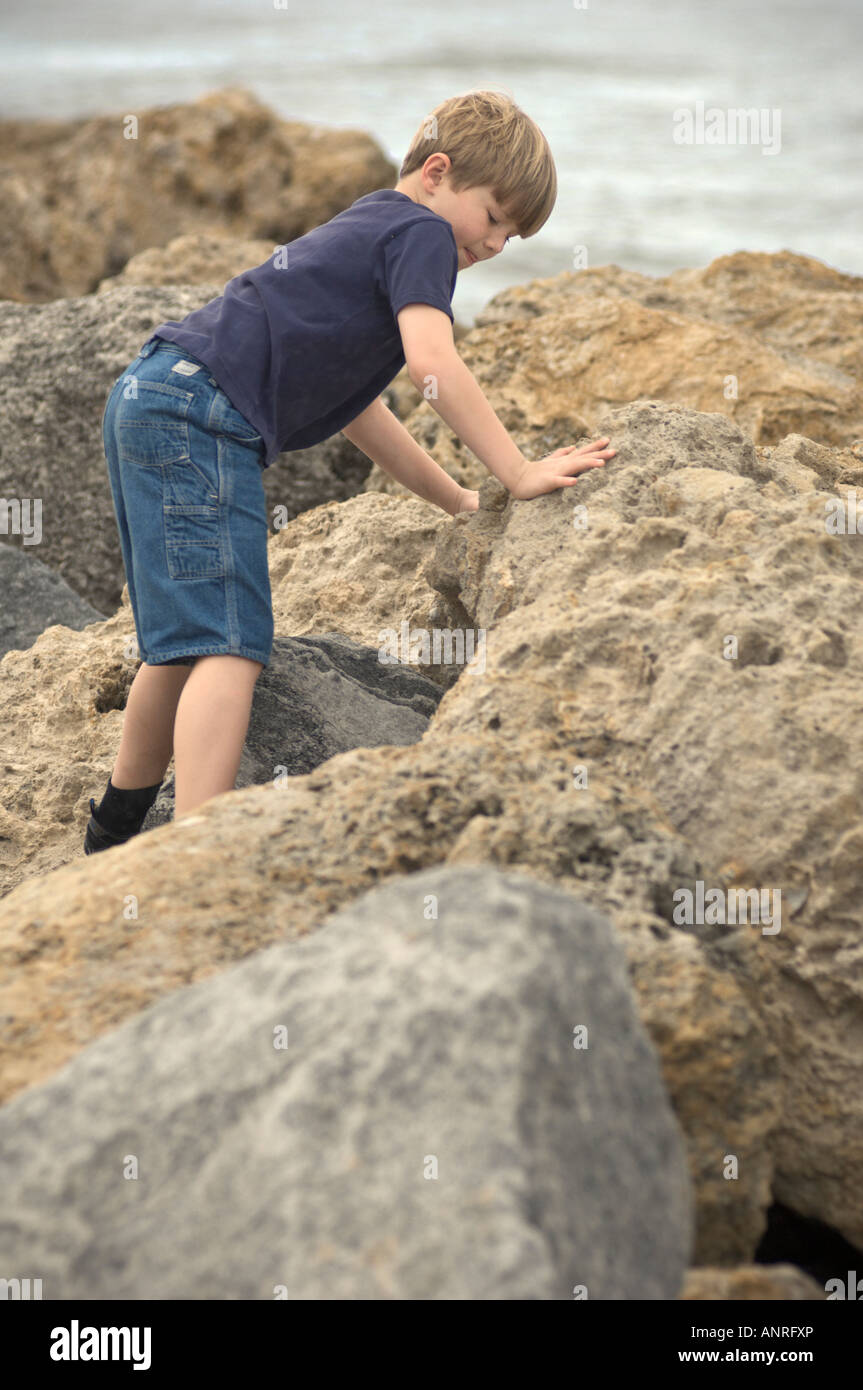 Boy climbing on rocks aventure balance enfant explorer Banque D'Images