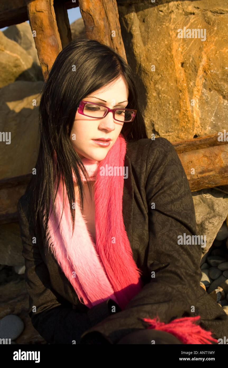 Adolescente, de longs cheveux noirs, écharpe rose et portant des lunettes, seule, par elle-même, à la triste et solitaire, UK Banque D'Images