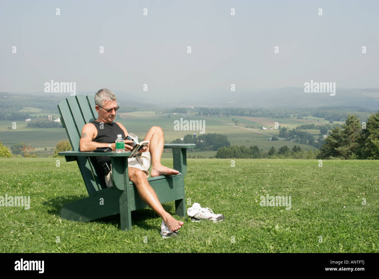 La lecture de l'homme en fauteuil Adirondak Banque D'Images