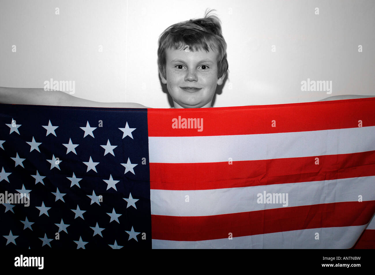 Un garçon de 13ans debout derrière le drapeau américain Stars & Stripes qu'il retient. Banque D'Images