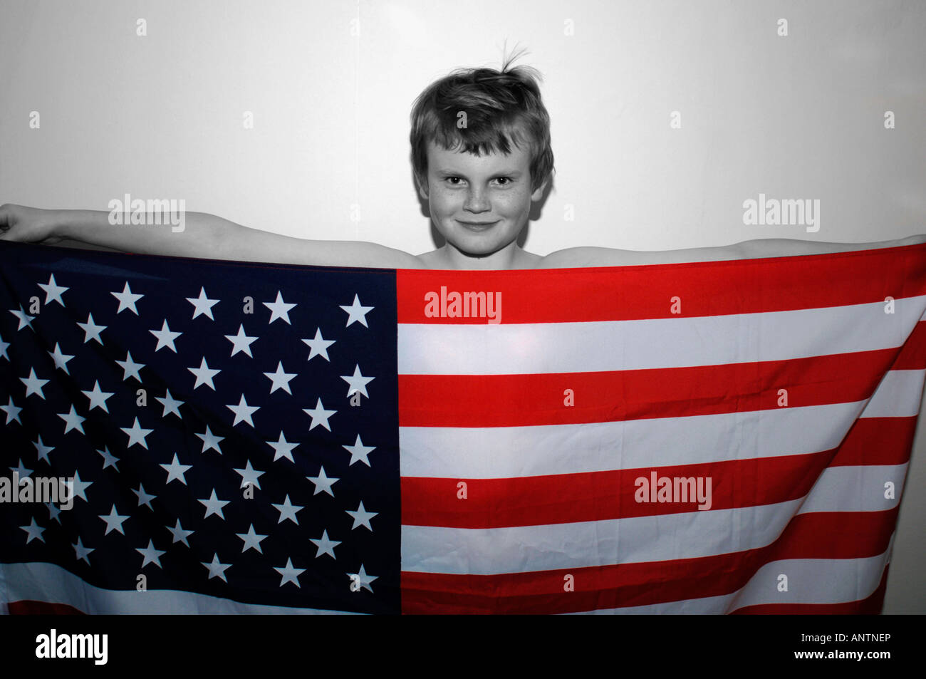 Un garçon de 13ans debout derrière le drapeau américain Stars & Stripes qu'il retient. Banque D'Images