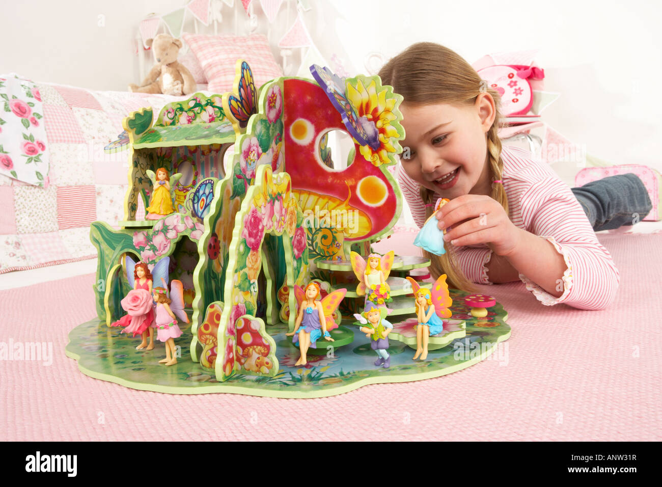 Une fille se pose sur le sol à jouer avec un jouet jeu fairy Banque D'Images