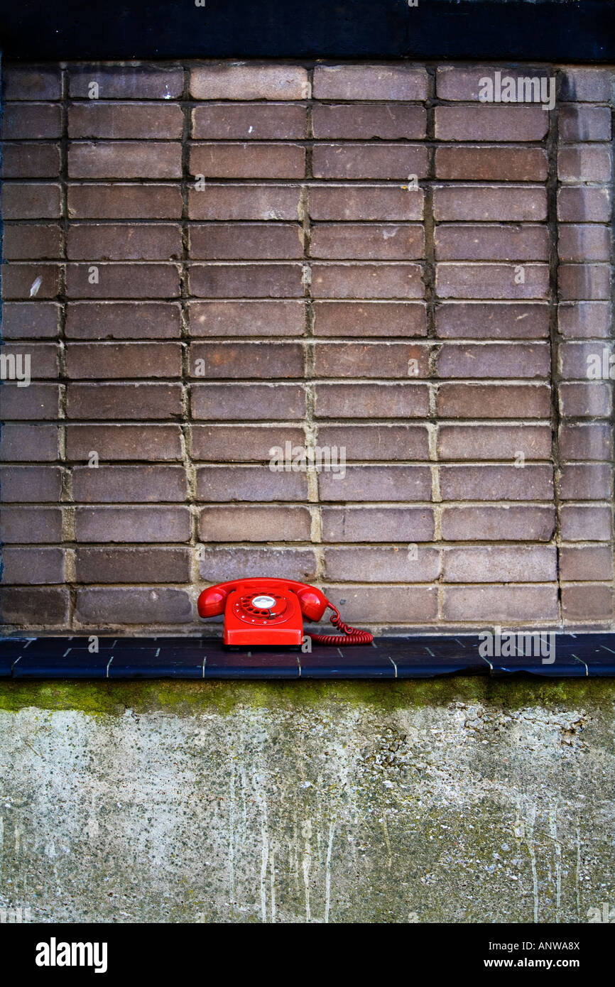 UK retro téléphone rouge contre un mur de briques Banque D'Images
