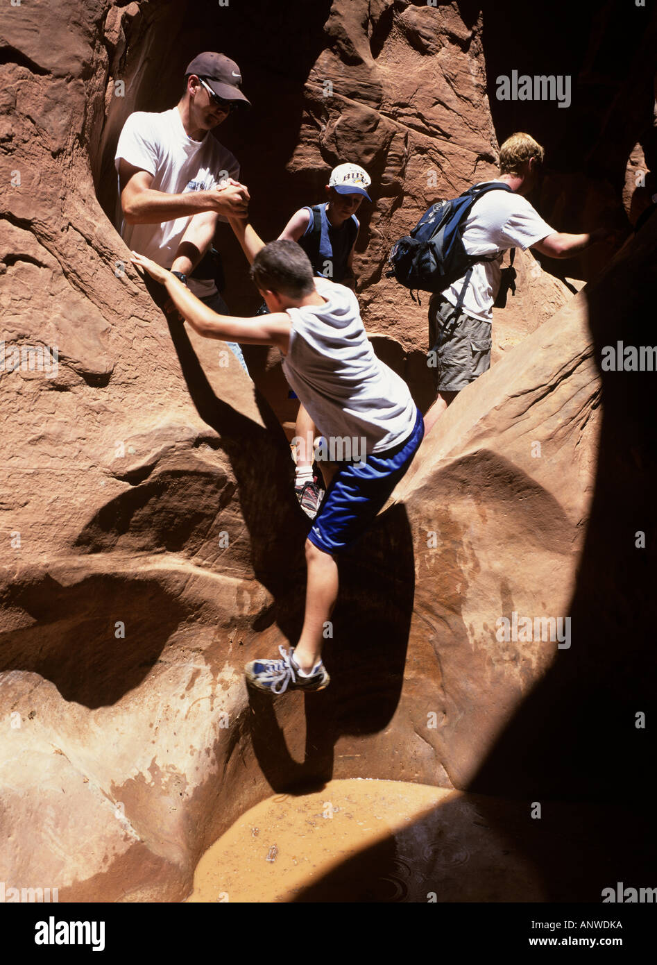 Randonneur grimper sur un étang dans le peek a boo Slot Canyon, grand escalier-escalante np, Utah, USA Banque D'Images