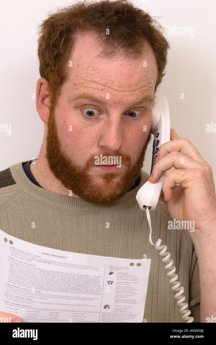 L'homme sur le téléphone en question des éléments sur ses relevés bancaires montrant surpris surprise ou d'horreur Banque D'Images