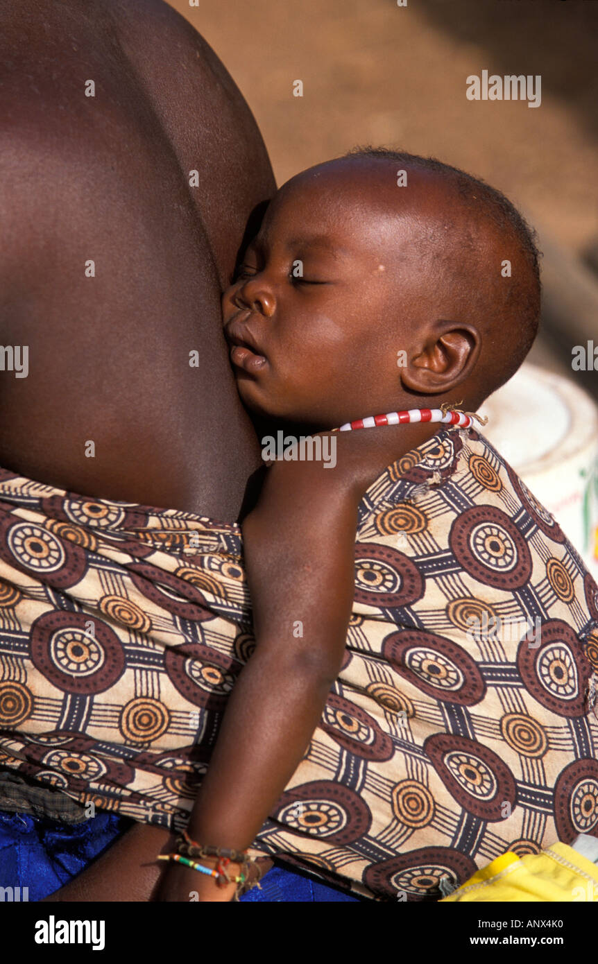 Un bébé qui dort dans un Bassari dling, c'est sur le dos de la mère, dans le village d'Icholo, au Sénégal, l'Afrique Banque D'Images