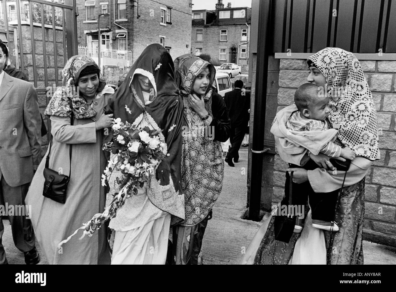 La mariée avec son visage couvert par un foulard sur le chemin de son mariage. Manningham, Bradford, Yorkshire, UK Banque D'Images