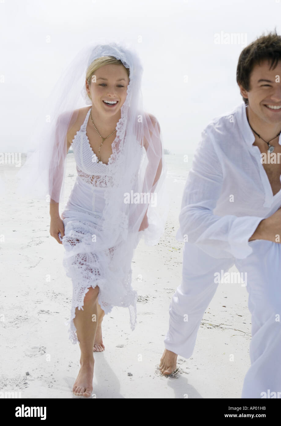 Bride and Groom running on beach Banque D'Images