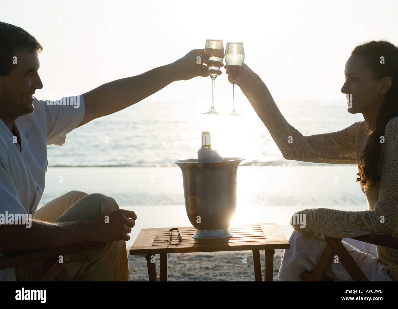 Jeune couple clinking champagne glasses on beach Banque D'Images