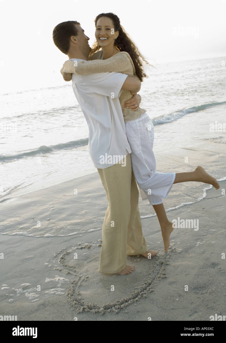 Jeunes mariés, l'homme ramasser woman on beach Banque D'Images