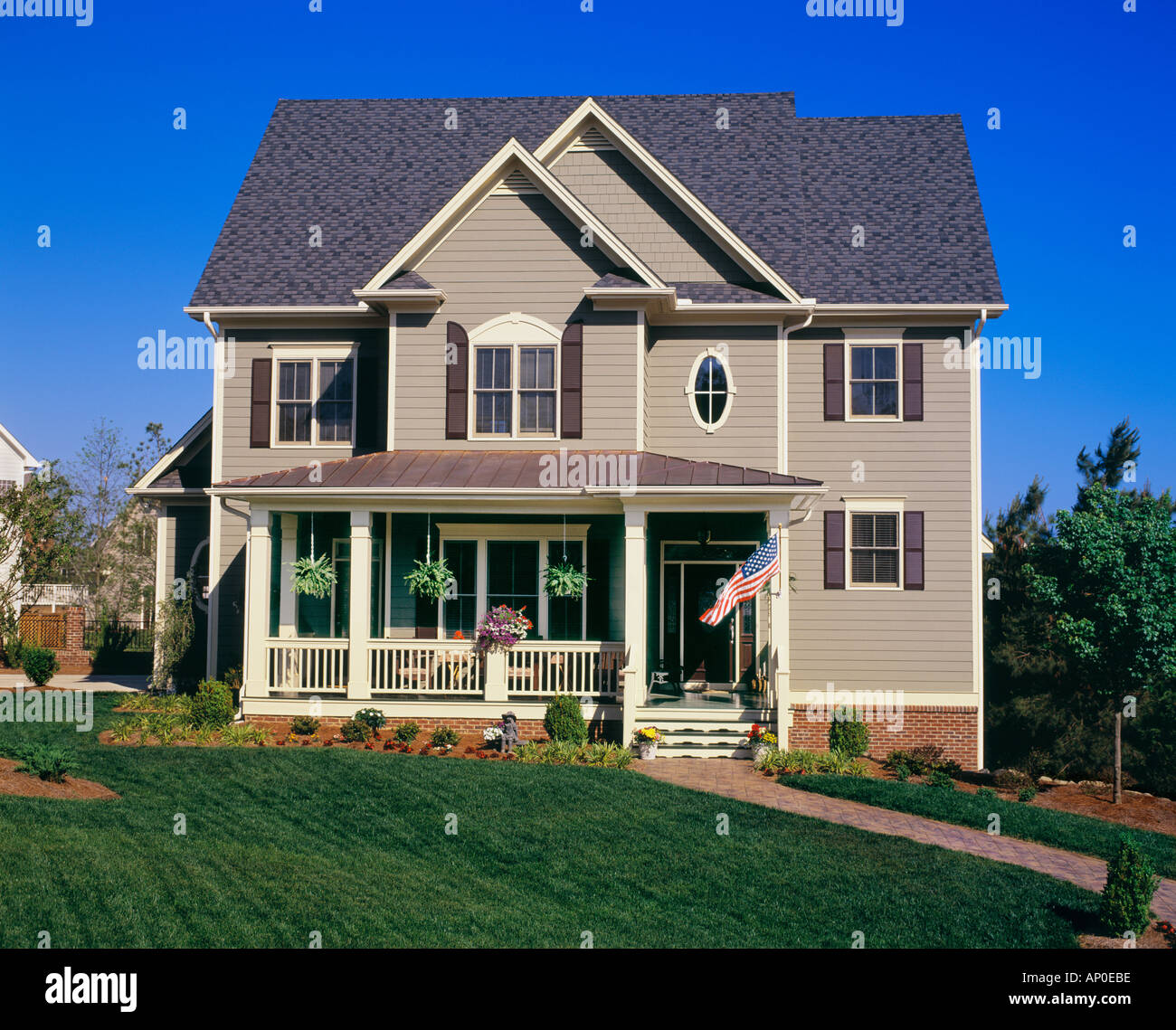 Vue de face d'une grande maison de deux étages marron avec des garnitures blanches et un grand porche et dans la cour Banque D'Images